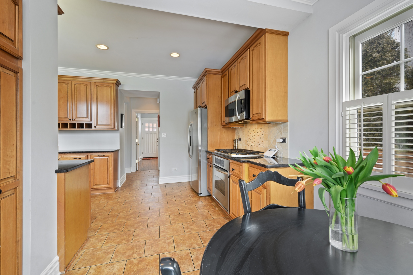 1054 Tower Road Winnetka, IL 60093 - Photo 16 of 32 a living room with stainless steel appliances kitchen island granite countertop furniture a rug a potted plant and a window
