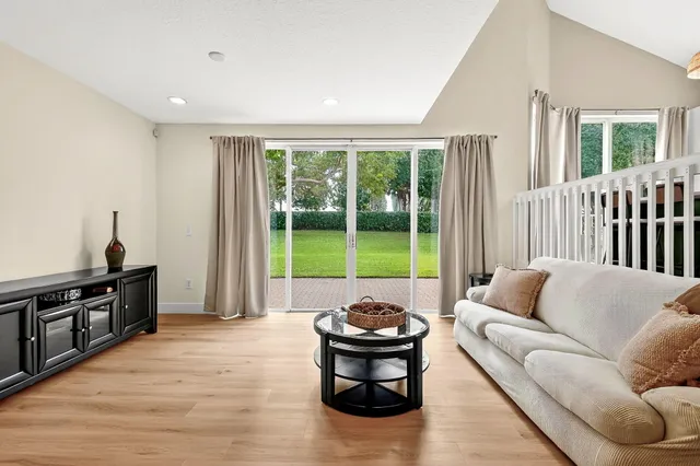 an empty room with wooden floor ceiling fan and windows