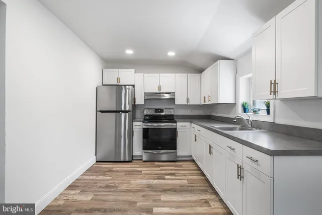 a kitchen with granite countertop a refrigerator and a stove top oven