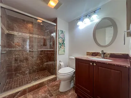 a bathroom with a granite countertop sink toilet and shower