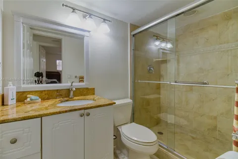 a bathroom with a granite countertop sink toilet and shower