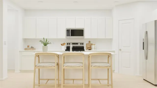 a white kitchen with stainless steel appliances granite countertop white cabinets and a refrigerator