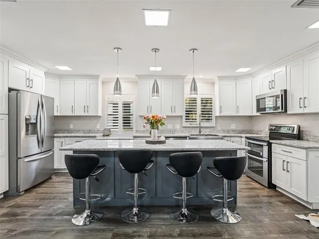 a kitchen with stainless steel appliances granite countertop a sink stove and refrigerator