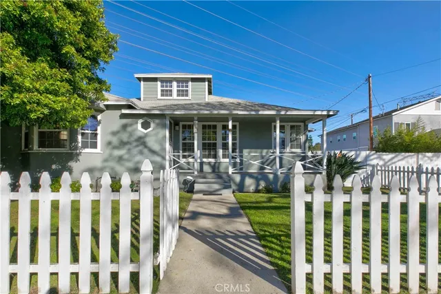 a front view of white house with wooden fence