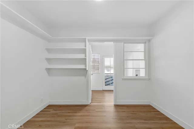a view of empty room with wooden floor and fan