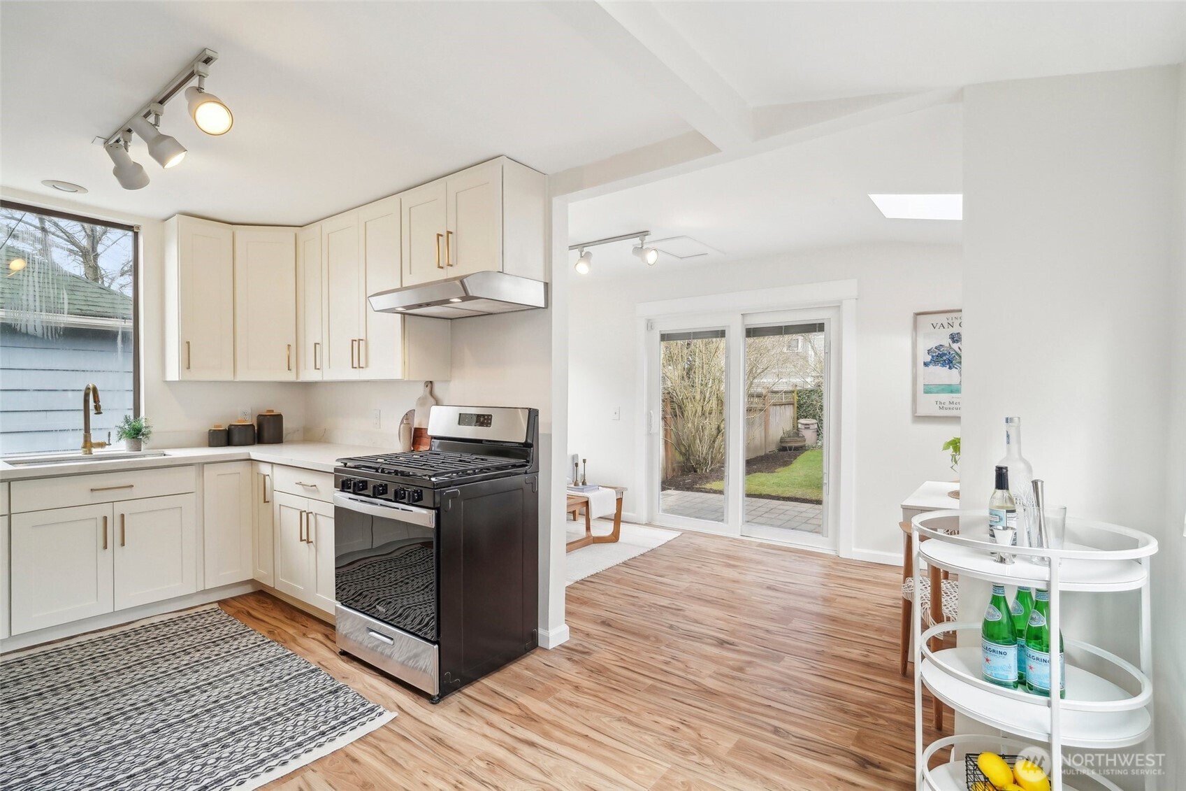 1420 North 50th Street Seattle, WA 98103 - Photo 10 of 32 a kitchen with stainless steel appliances granite countertop a stove top oven a sink dishwasher and white cabinets with wooden floor