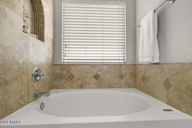 a white bath tub sitting in a bathroom next to a window