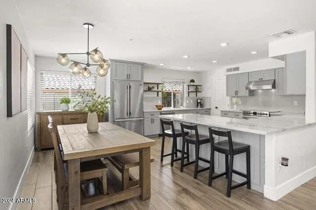 a kitchen with stainless steel appliances granite countertop a stove top oven a sink dishwasher and white cabinets with wooden floor