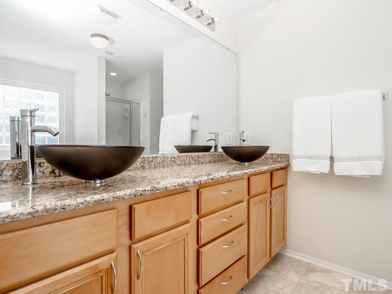 8507 Flying Buttress Drive Raleigh, NC 27613 - Photo 11 of 27 Vessel sinks on a granite counter, marble floors, a garden tub and a separate shower.