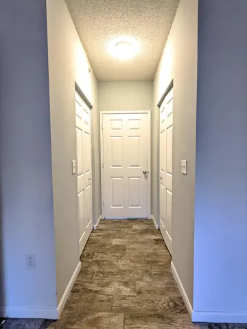 a view of a hallway to a bedroom with wooden floor and a bathroom