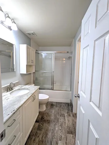 a bathroom with a granite countertop sink toilet and shower