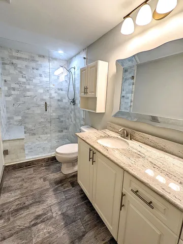 a bathroom with a granite countertop sink mirror vanity and toilet