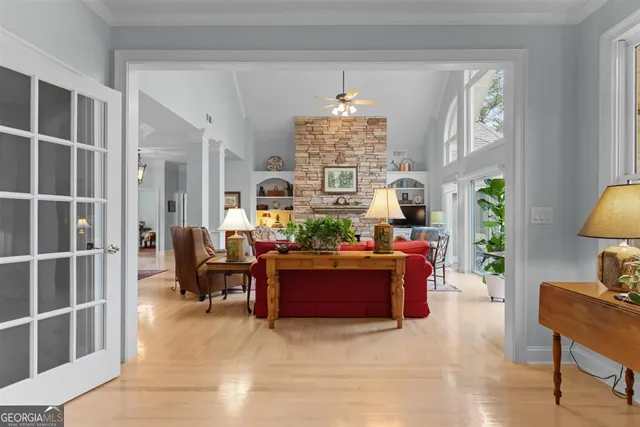 a view of a dining room and livingroom with furniture wooden floor a rug a fireplace and a chandelier