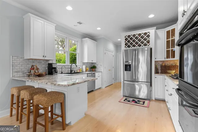 a kitchen with stainless steel appliances granite countertop a stove top oven a sink a dining table and chairs