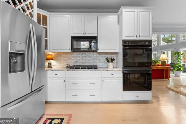 a kitchen with granite countertop white cabinets and stainless steel appliances