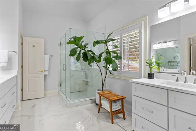 a bathroom with a shower a mirror and a plant