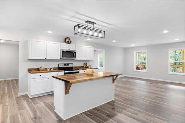 a kitchen with granite countertop a stove top oven a sink dishwasher and white cabinets with wooden floor
