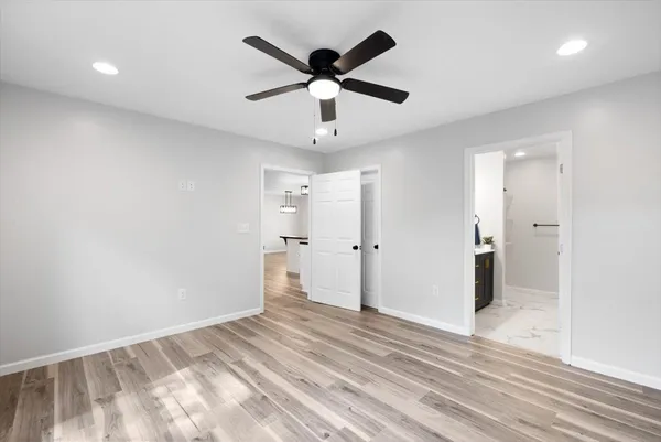 a view of empty room with wooden floor and ceiling fan