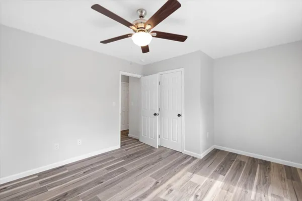an empty room with wooden floor and a ceiling fan