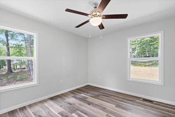 a view of empty room with wooden floor and fan
