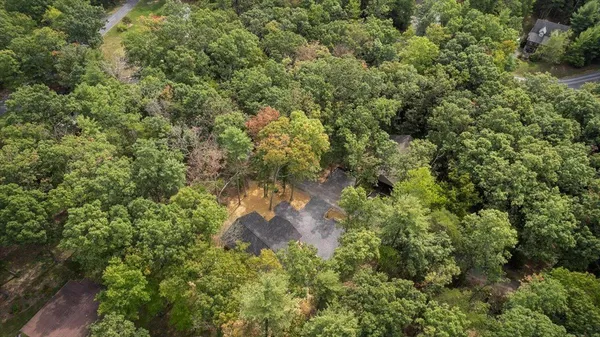an aerial view of residential house with outdoor space and trees all around