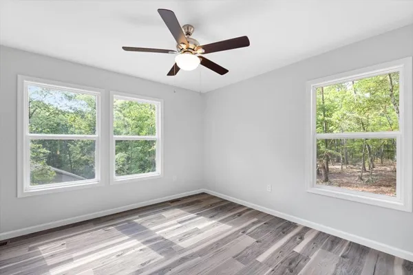 a view of empty room with wooden floor and fan
