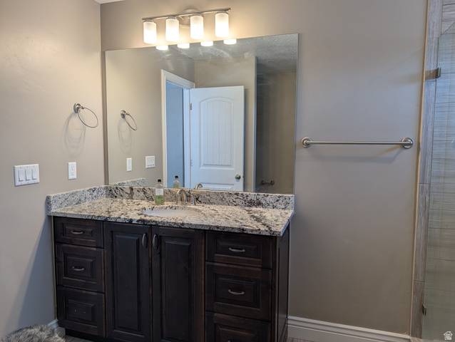 171 South Mustang Road East Grantsville, UT 84029 - Photo 15 of 41 Contemporary bathroom vanity featuring a granite countertop, undermount sink, and dark wood-finish cabinetry with multiple drawers