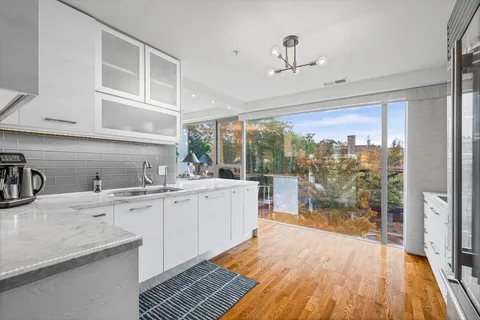a kitchen with sink a refrigerator and glass cabinets