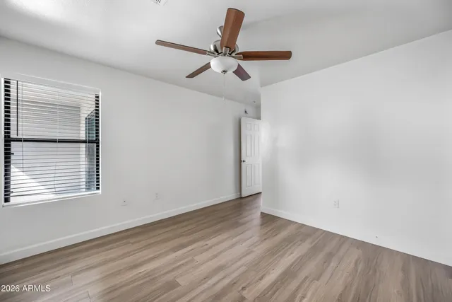 an empty room with wooden floor and a ceiling fan