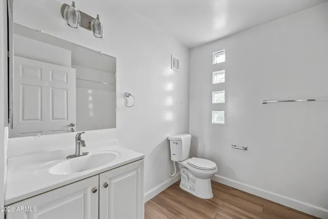 an empty room with wooden floor ceiling fan and windows