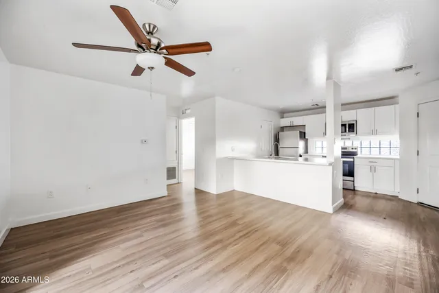 an empty room with wooden floor fan and windows