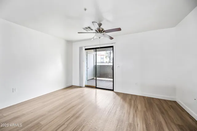a view of empty room with wooden floor and ceiling fan