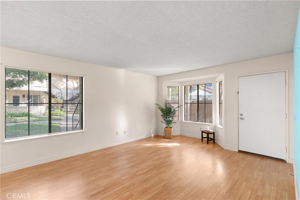 12621 Moordale Circle, Unit G Stanton, CA 90680 - Photo 10 of 36 a view of an empty room with a window and wooden floor