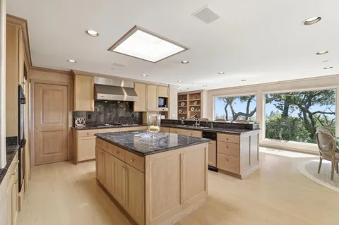 a kitchen with stainless steel appliances granite countertop a stove a sink a refrigerator and white cabinets with wooden floor
