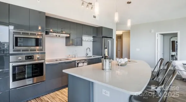 a kitchen with stainless steel appliances a dining table chairs and stove