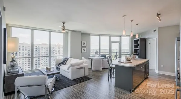 a living room with furniture large windows and wooden floor