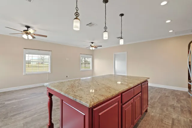 a kitchen with a center island chandelier and wooden floor