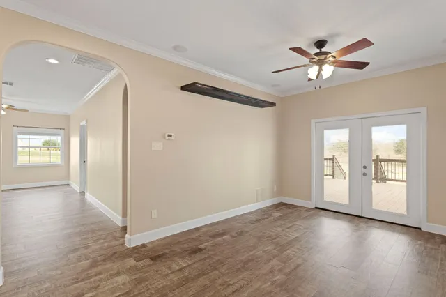 a view of an empty room with window and wooden floor