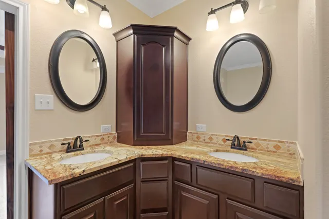 a bathroom with a granite countertop double vanity sink and a mirror