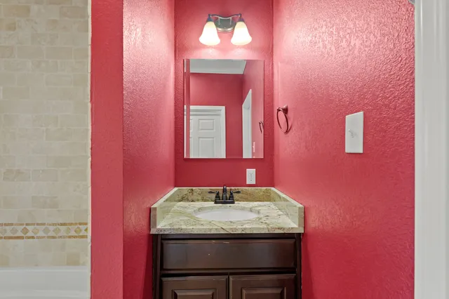 a bathroom with a granite countertop sink and a mirror