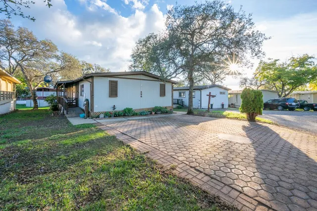 a view of a white house with a yard and large tree