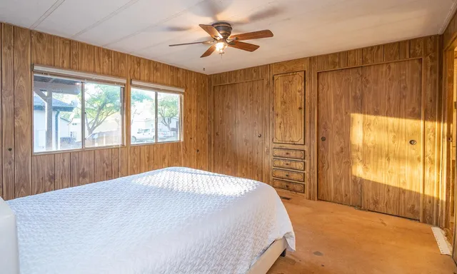 a bedroom with a large bed and a chandelier fan