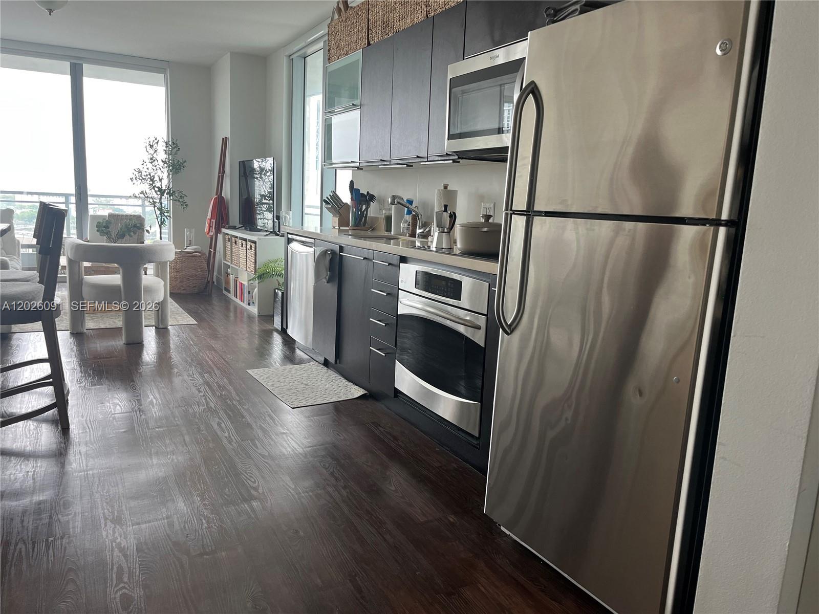 90 Southwest 3rd Street, Unit 1705 Miami, FL 33130 - Photo 2 of 33 a kitchen with granite countertop a refrigerator a sink dishwasher a stove and a refrigerator with wooden floor