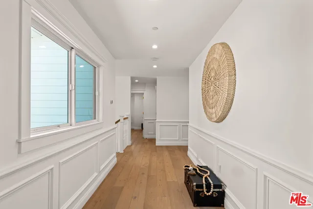 a view of a hallway with wooden floor and a bathroom view