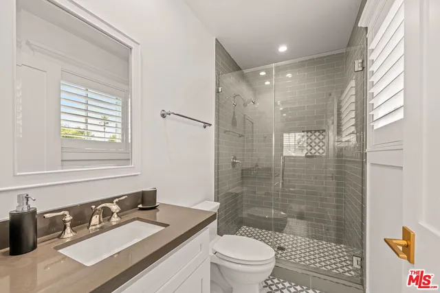 a bathroom with a sink a toilet a mirror and shower