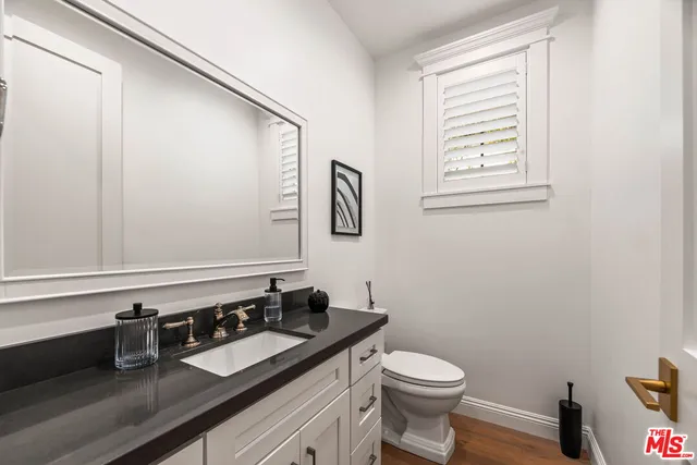 a bathroom with a granite countertop sink and a toilet