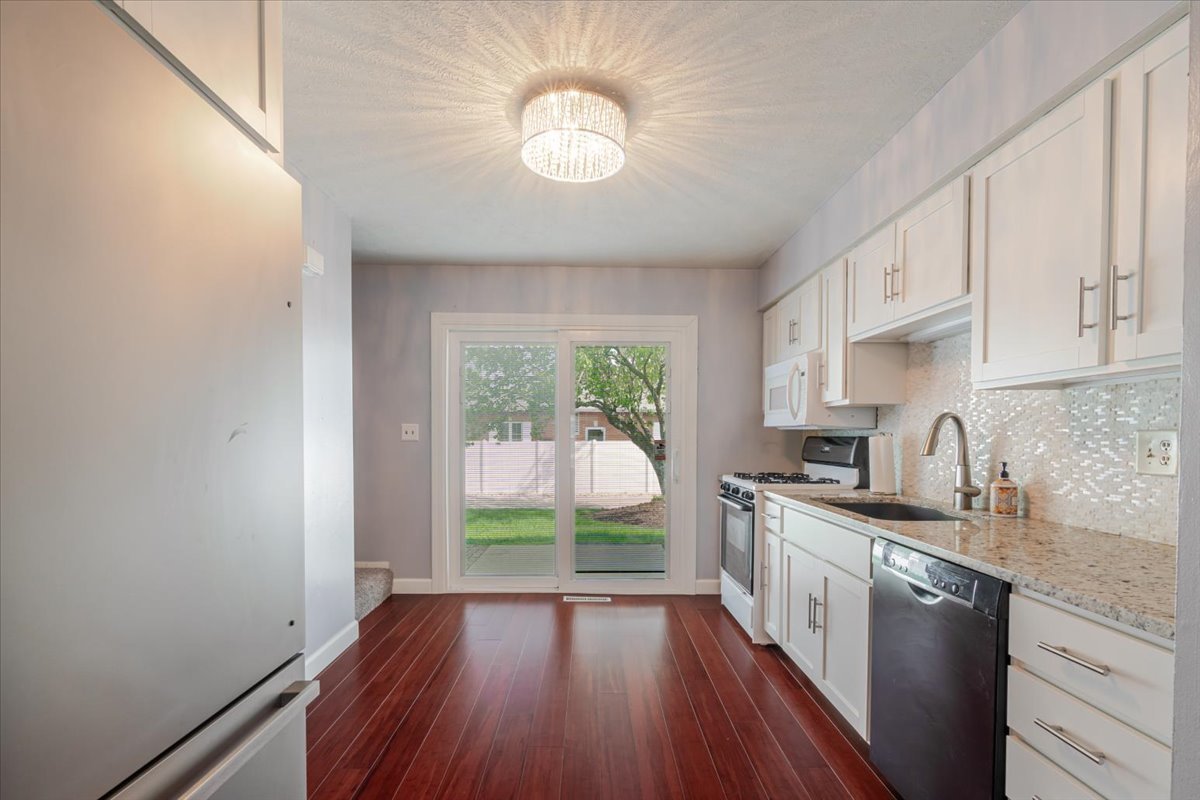 103 South Towanda Avenue, Unit 3 Normal, IL 61761 - Photo 6 of 17 a kitchen with granite countertop a stove a sink a refrigerator wooden floor and cabinets
