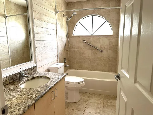 a bathroom with a granite countertop sink toilet and shower
