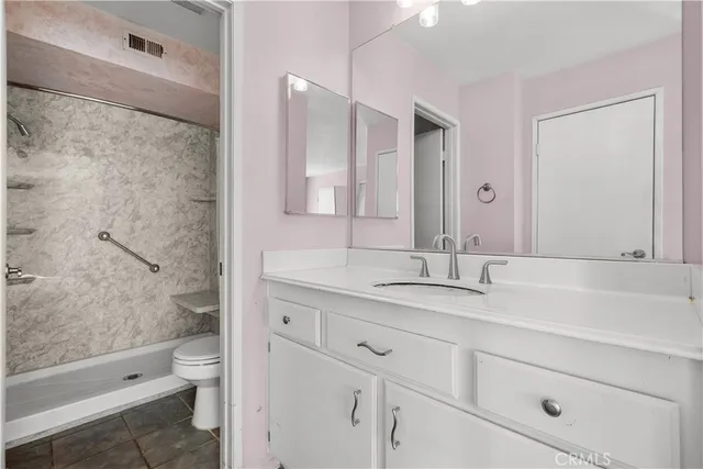 a bathroom with a granite countertop sink toilet and shower