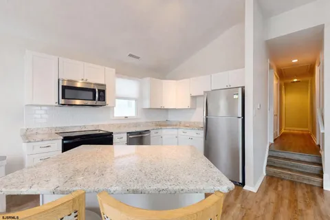 a kitchen with stainless steel appliances granite countertop a refrigerator a stove top oven a sink and dishwasher